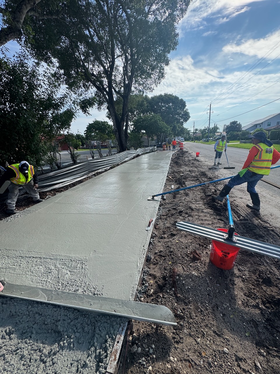 Workers smoothing a concrete sidewalk