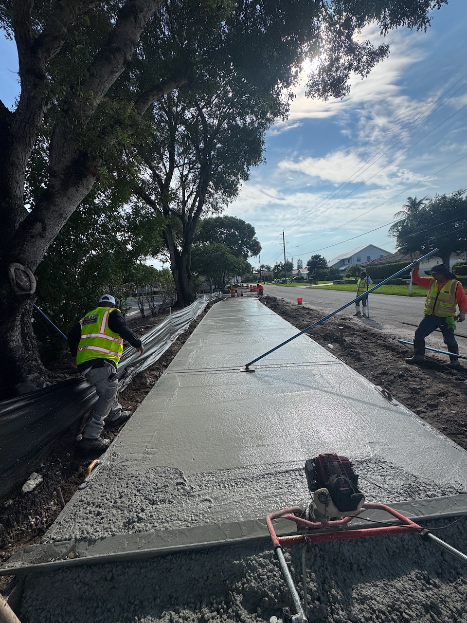 Crew finishing a freshly poured concrete sidewalk