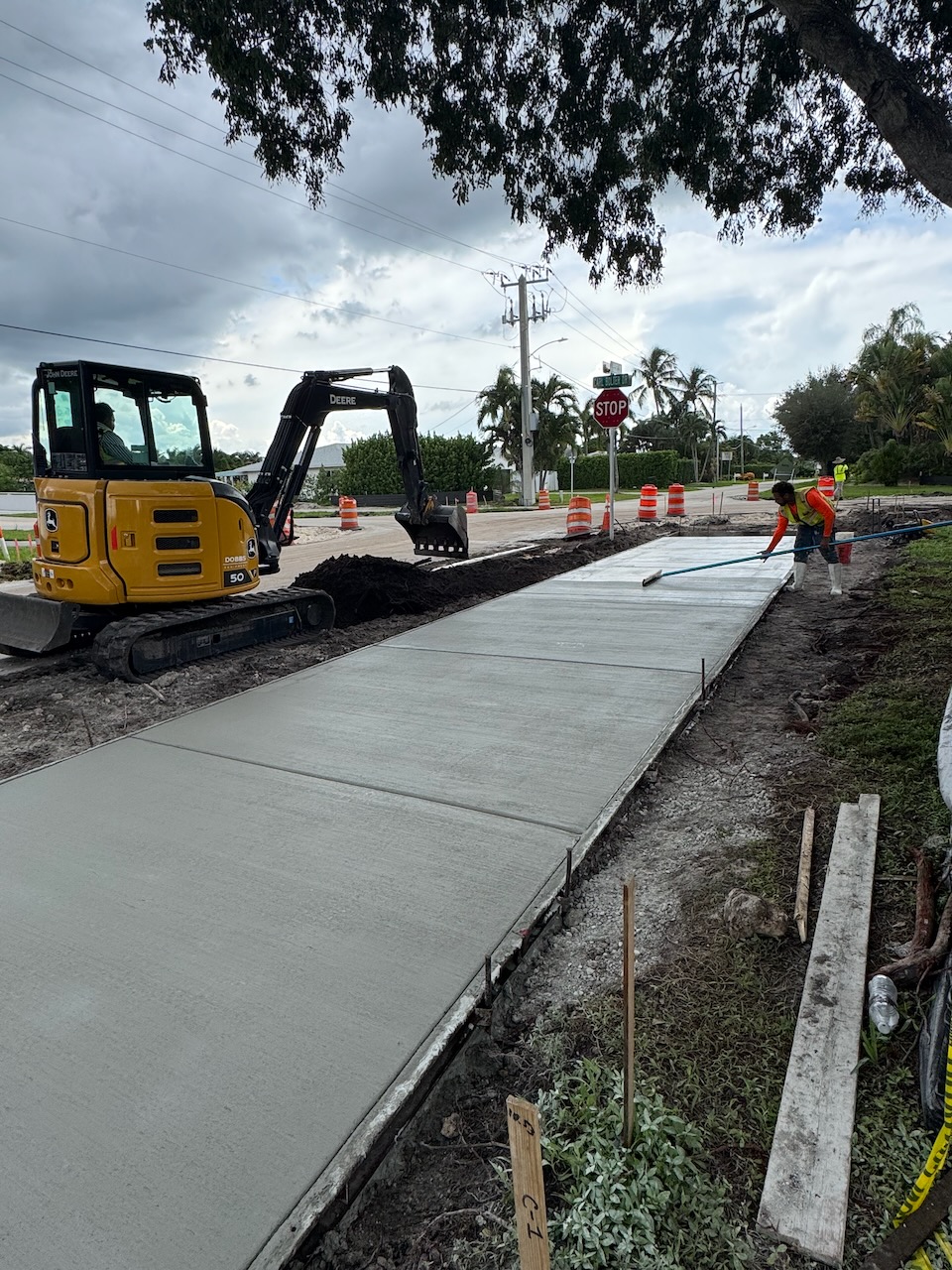 Excavator and crew beside a newly finished sidewalk