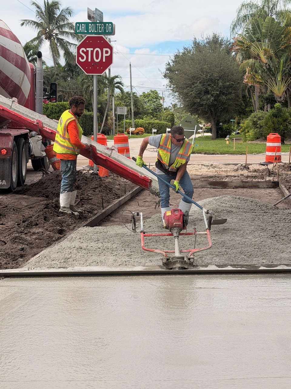 Workers placing concrete beside a mixer truck