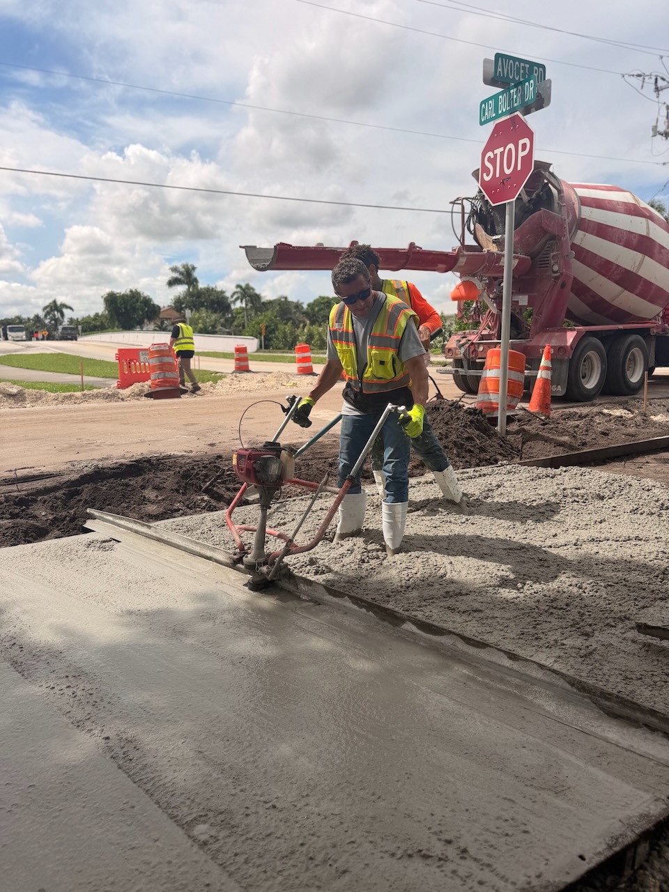 Crew compacting concrete beside a mixer truck