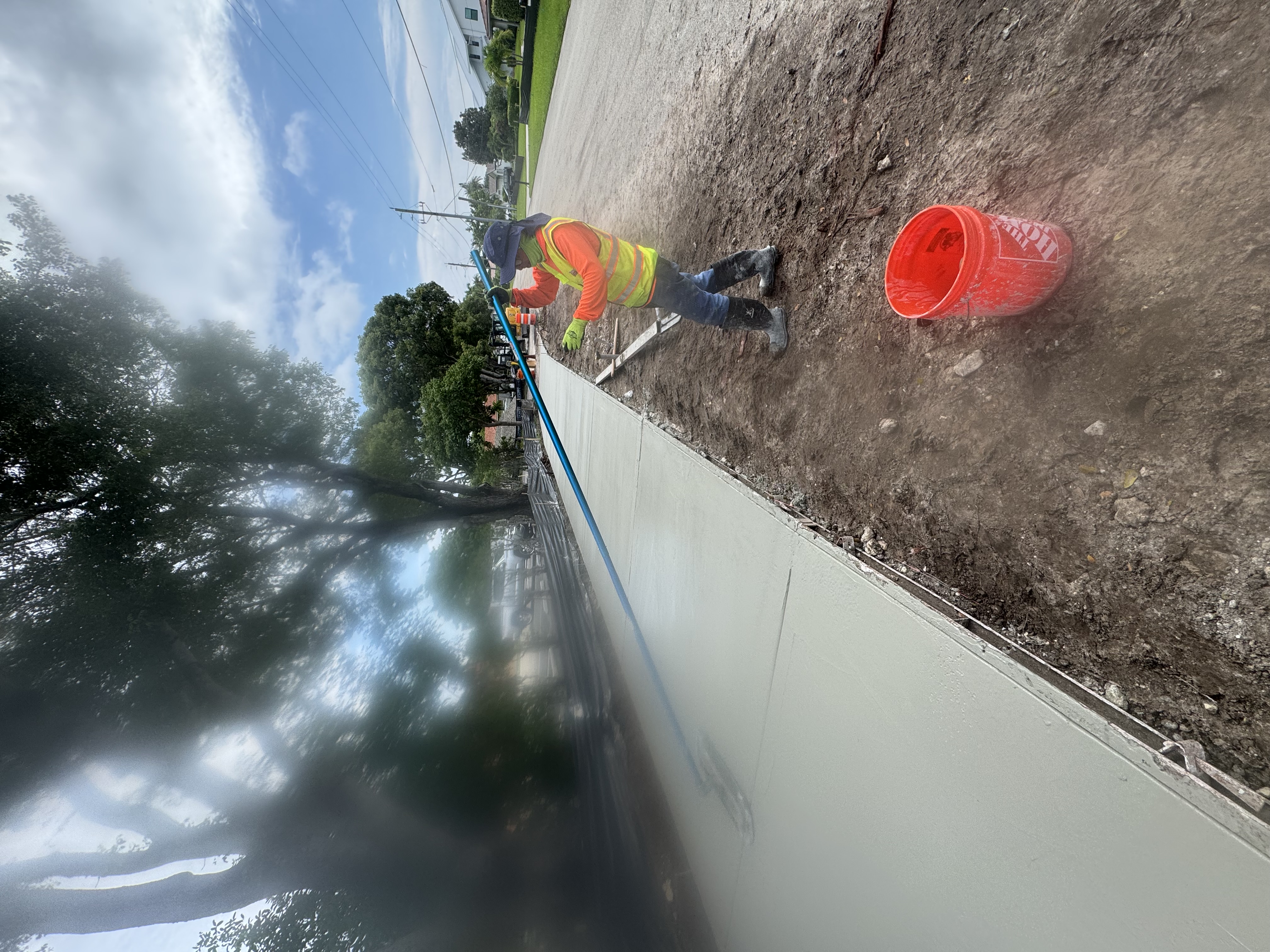Crew and machinery working alongside a new sidewalk